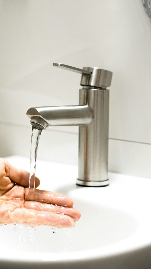 A family fills a glass of water from a kitchen faucet in a typical home setting.