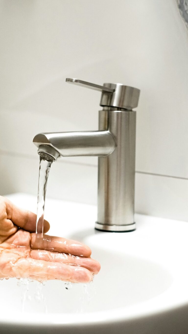 A family fills a glass of water from a kitchen faucet in a typical home setting.